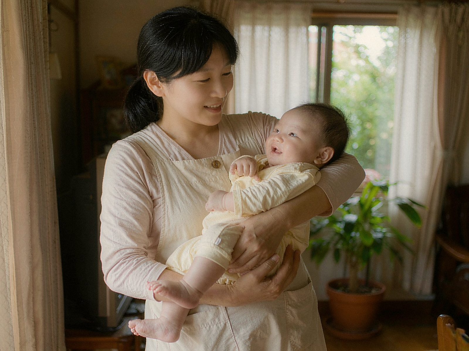 中国育婴师在暖光客厅陪宝宝玩积木的温馨画面